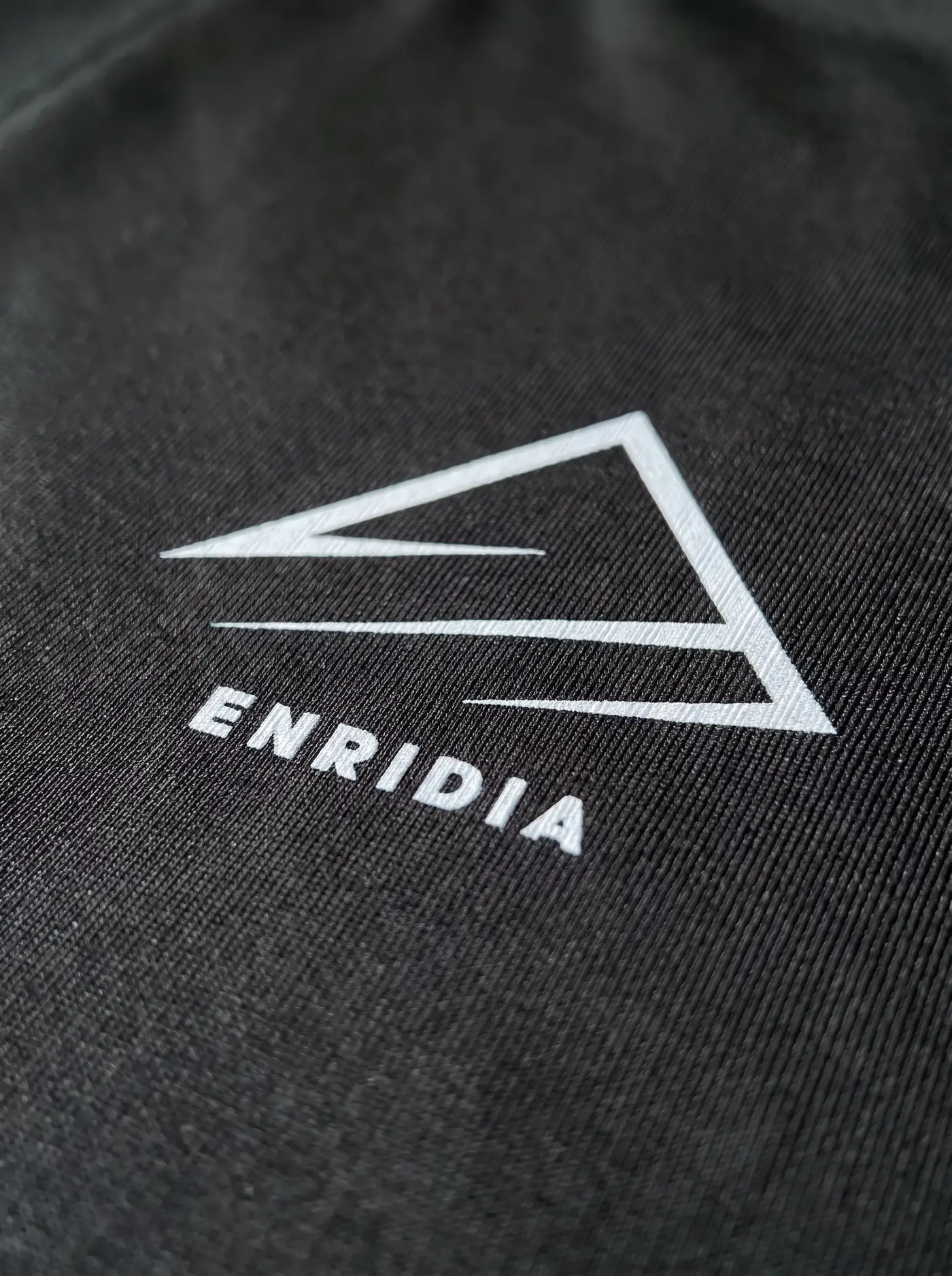 Detalle del isotipo de Enridia sobre tejido de compresión negro