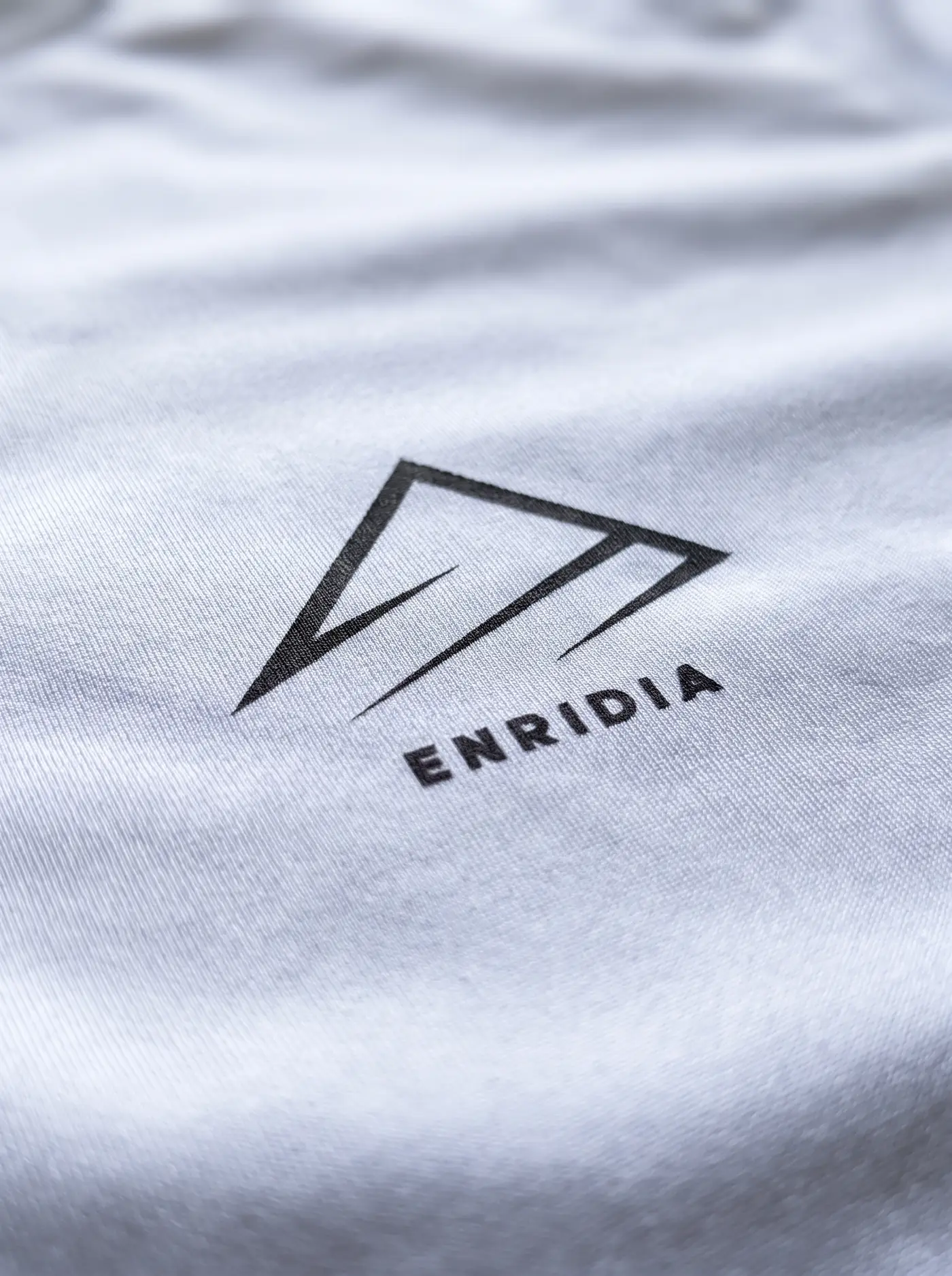 Detalle del isotipo de Enridia sobre tejido de compresión blanco