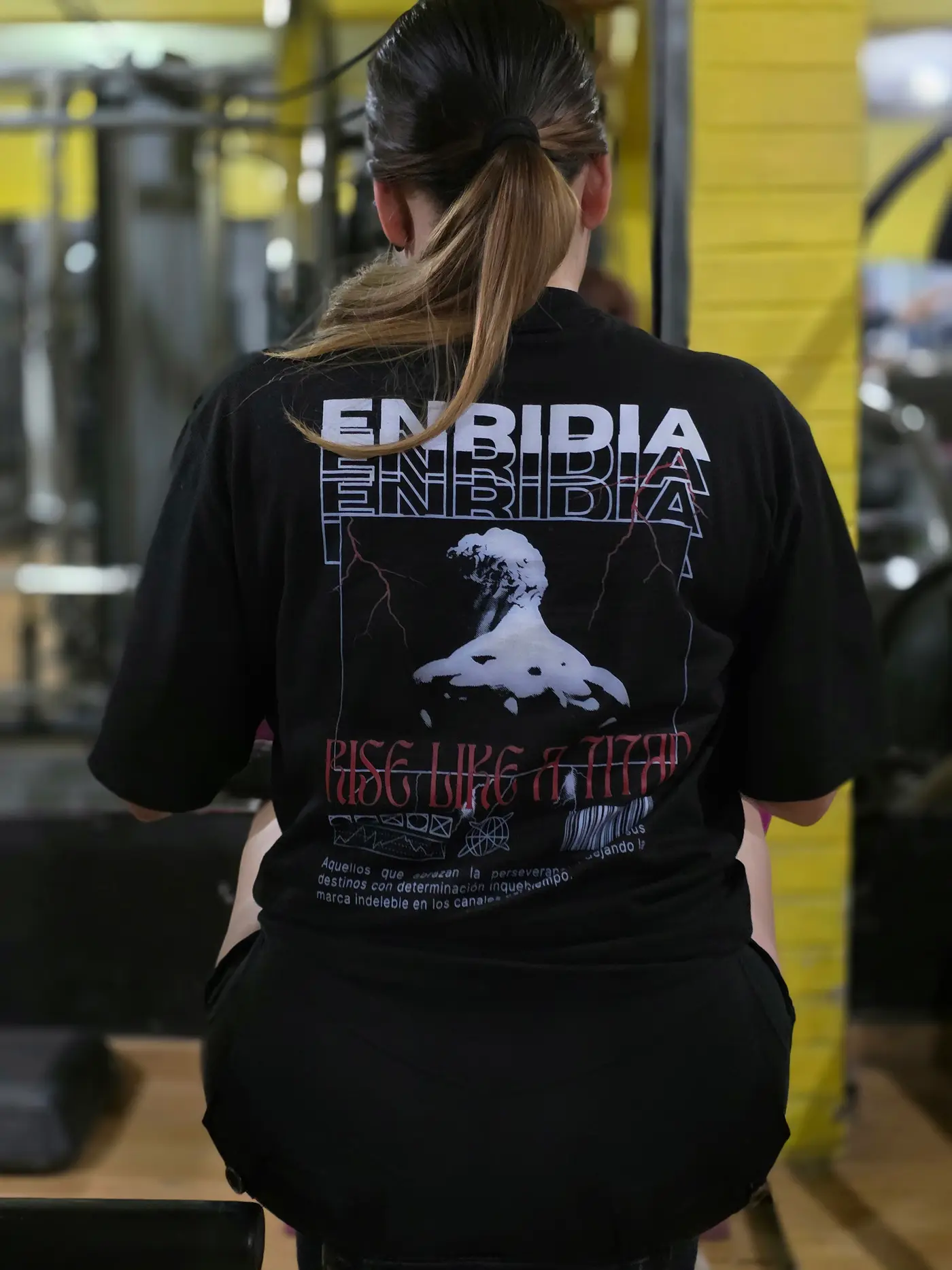 Oversize Rise Like a Titan en negro, visto de espalda en el gimnasio