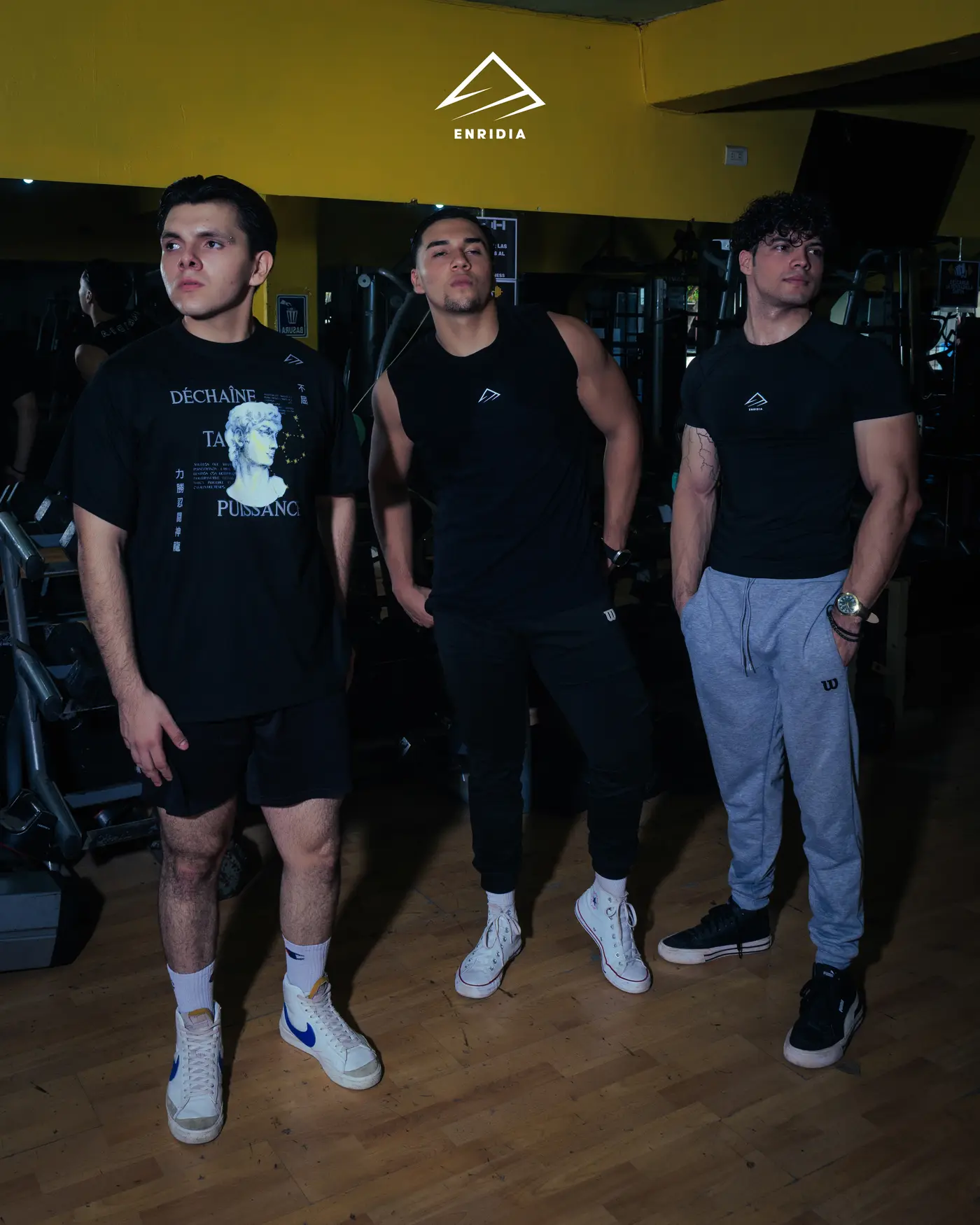 Tres personas con prendas de la primera colección de Enridia en un gimnasio